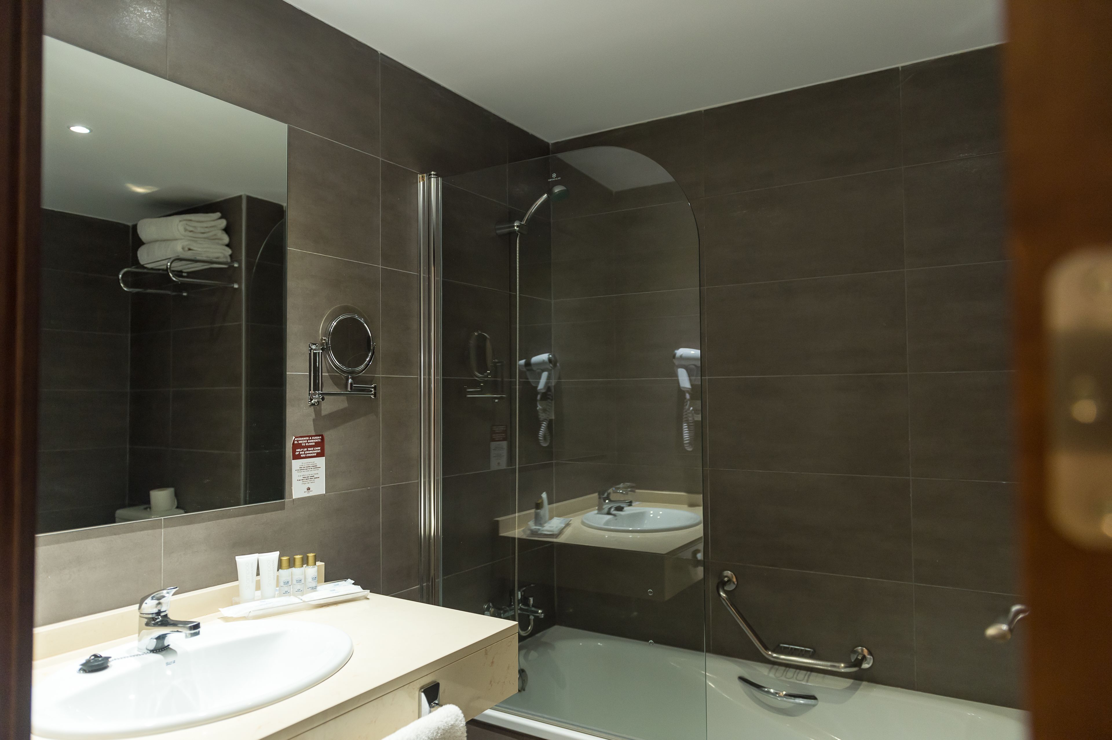 A modern bathroom with a glass-enclosed shower, a sink, and a mirror.