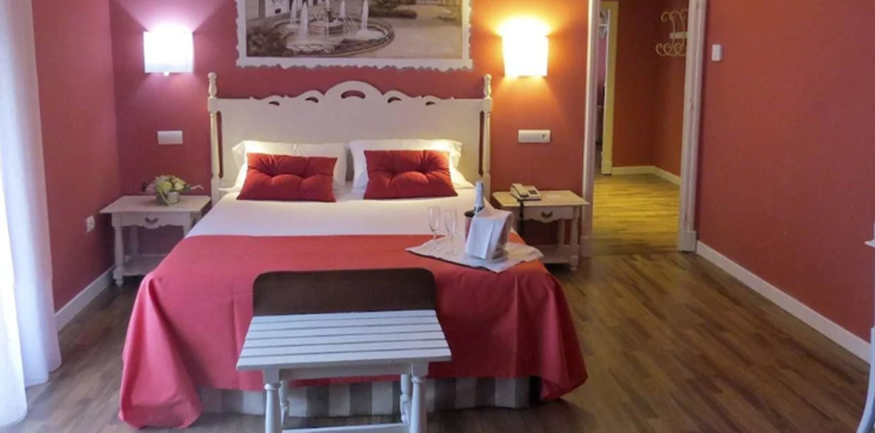A hotel room with a bed, two bedside tables, a nightstand, a desk, and a chair.