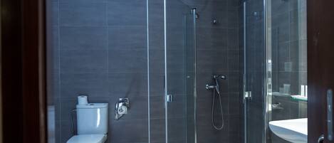 Un baño moderno con ducha de vidrio, inodoro y lavamanos.