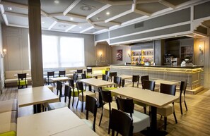 Enjoy meals in a stylish dining area with multiple tables and chairs, a bar, and a modern ceiling design.