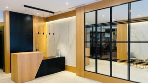 Un área de recepción moderna con un mostrador de madera, una barra negra y un amplio ventanal que ofrece vistas del espacio interior.