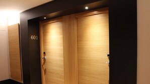 Una habitación de hotel con un amplio armario de madera, el número '601' en la pared y suelo de madera.