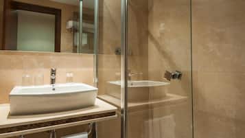 Un baño moderno con cabina de ducha de vidrio, lavamanos blanco y encimera de mármol.