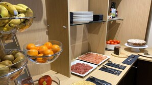 Een buffet met verschillende gerechten, waaronder fruit, vlees en een taart.