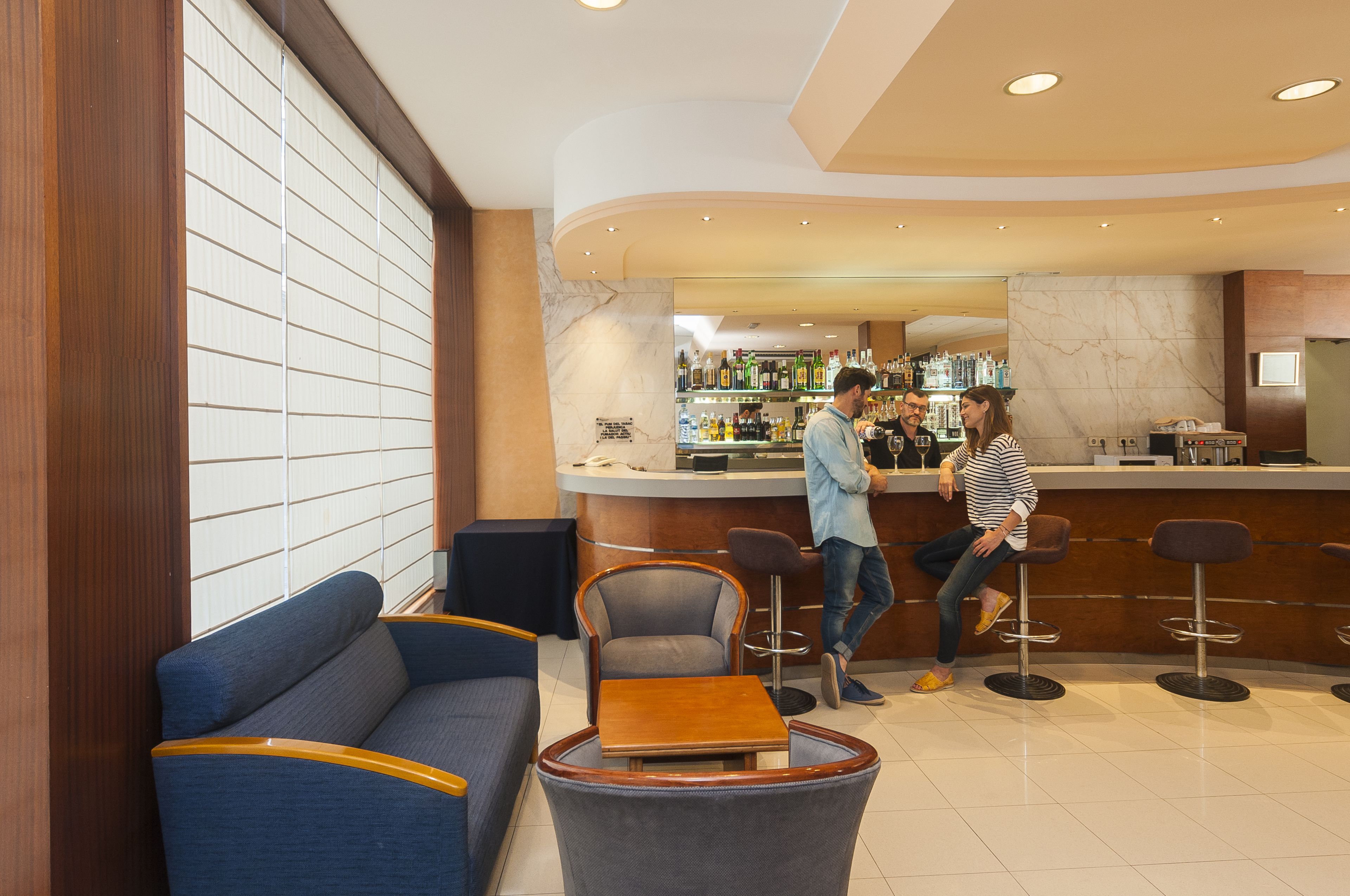 A bar area with seating, a counter, and a view of the bar shelves.