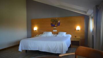 A hotel room with a large bed, two bedside tables, a nightstand, a chair, and a small table.