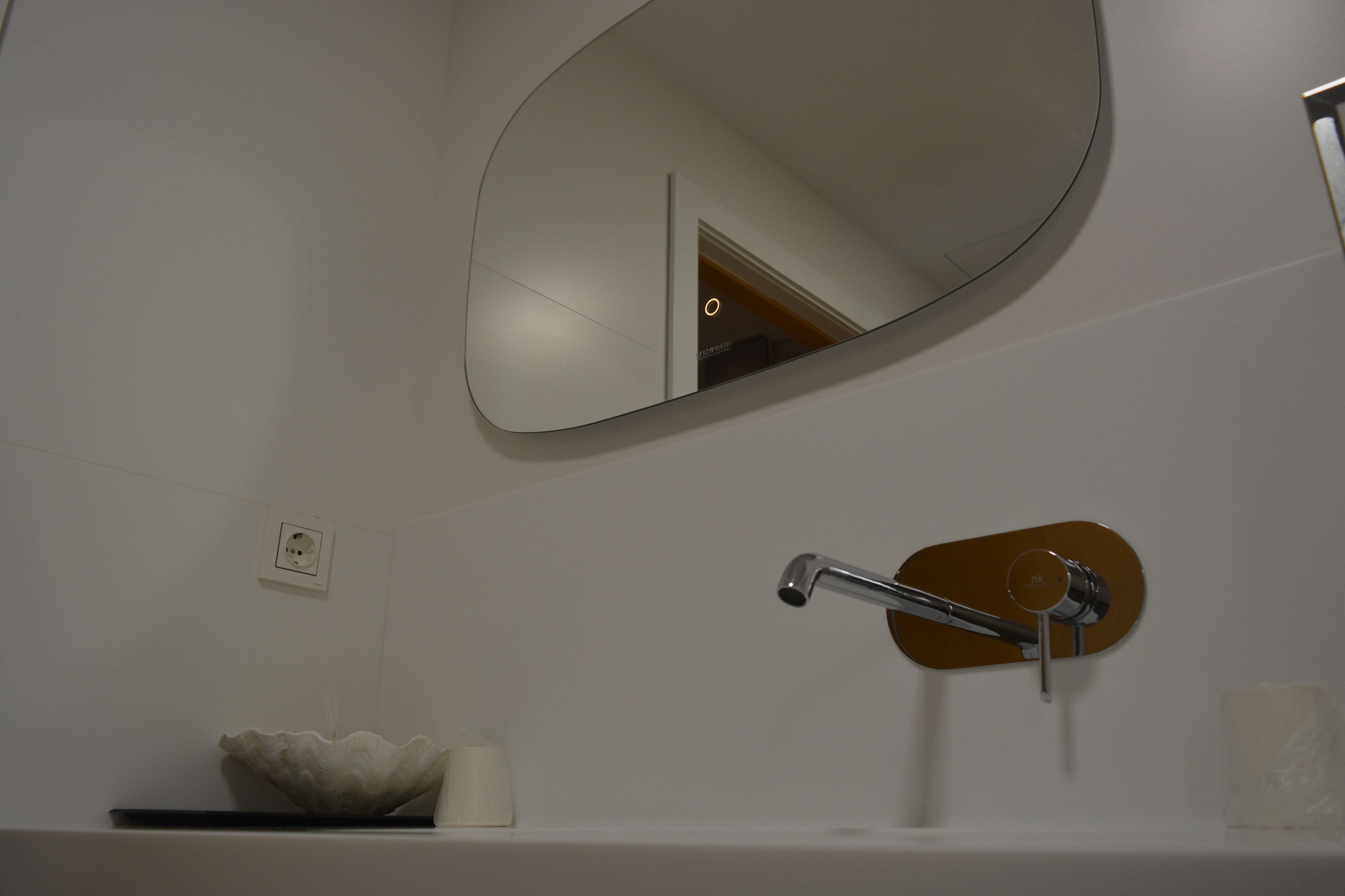 A bathroom with a round mirror, a sink with a modern faucet, and a decorative bowl.