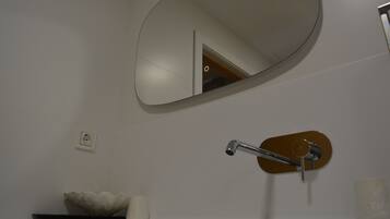 A bathroom with a round mirror, a sink with a modern faucet, and a decorative bowl.