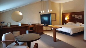 A hotel room with a desk, a television, a bed, a round table, and a chair. - Ruta Jacobea (Santiago de Compostela)