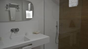 A modern bathroom with a white sink, mirror, and shower.