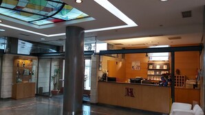 A hotel lobby with a reception desk, a large pillar, and a stained glass ceiling. - Ruta Jacobea (Santiago de Compostela)
