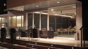 An outdoor seating area with modern furniture and glass partitions, providing a view of the interior. - Ruta Jacobea (Santiago de Compostela)