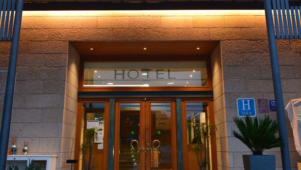 A hotel entrance with a stone facade, a wooden canopy, and potted plants. - Ruta Jacobea (Santiago de Compostela)