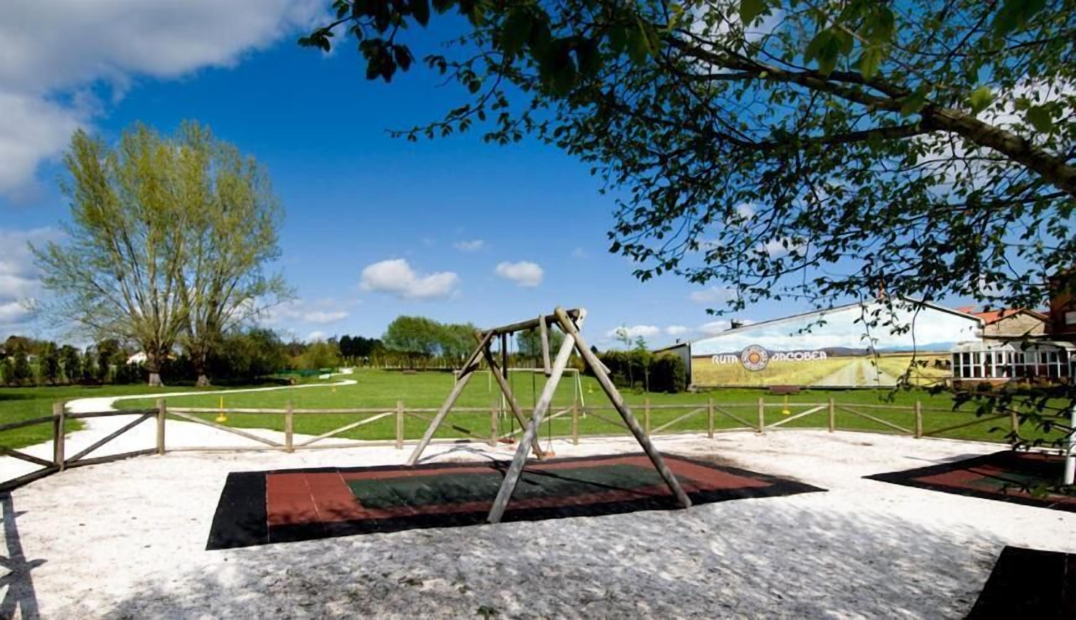 Un parc avec une balançoire, un terrain herbeux et un bâtiment orné d’une banderole.