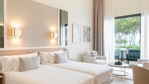 Una habitación de hotel moderna con dos camas, una zona de estar con una mesa y vistas al exterior.