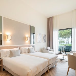 Ein modernes Hotelzimmer mit zwei Betten, einer Sitzecke mit Tisch und Blick ins Freie.