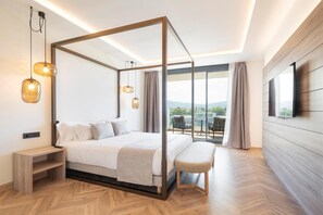 Un dormitorio moderno con cama con dosel, una banca, televisión y balcón con vistas.