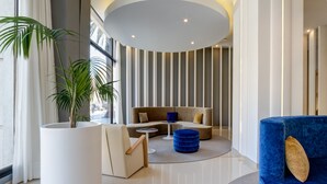 Un interior moderno con techo curvo, una zona de estar con sofá y reposapiés, una planta en maceta y un ventanal grande.