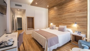 Habitación de hotel moderna con techo de madera, una cama grande, mesitas de noche, un escritorio con una silla y un televisor.