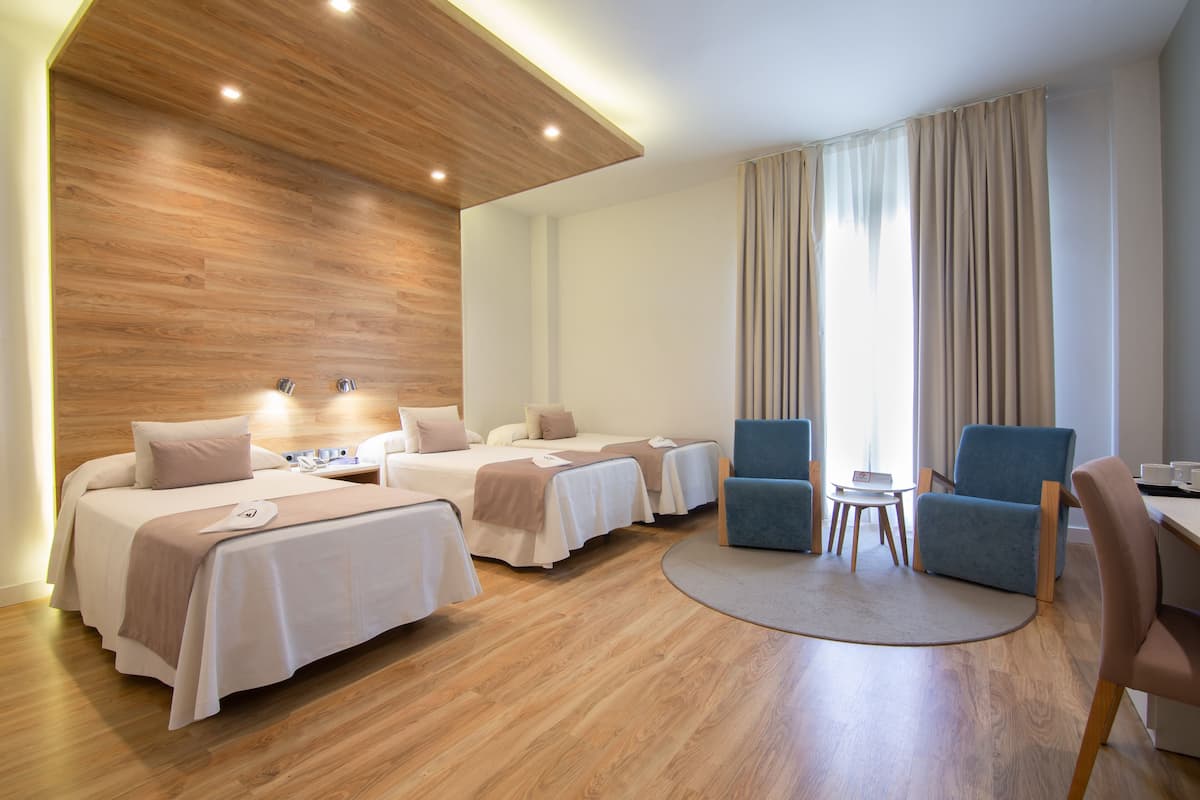 Una habitación de hotel con dos camas, un escritorio, una silla y una mesita.
