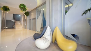 Un vestíbulo moderno con una escalera, un mostrador de recepción y un original mobiliario escultórico.