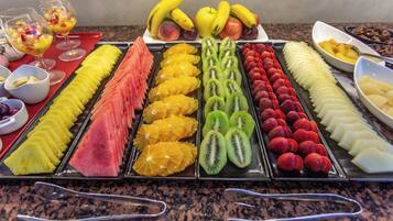Una bandeja de frutas con diversas frutas cortadas y un vaso de ensalada de frutas.
