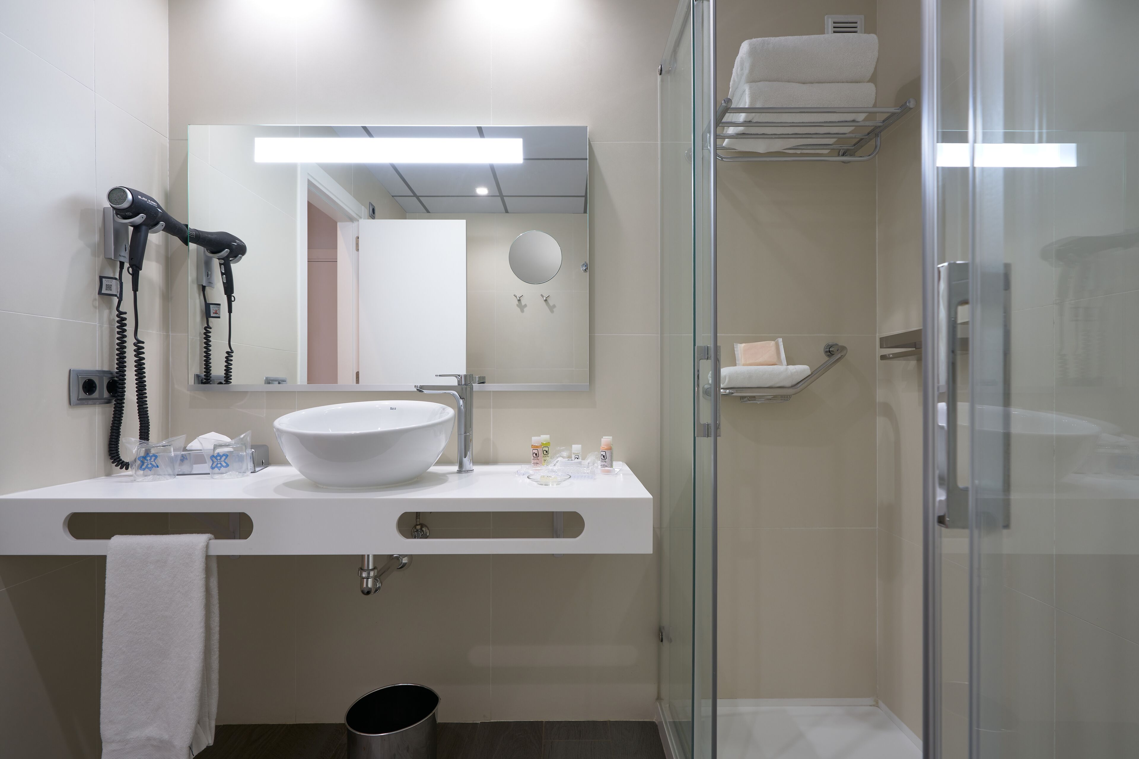 A modern bathroom with a large sink, mirror, and glass shower enclosure.