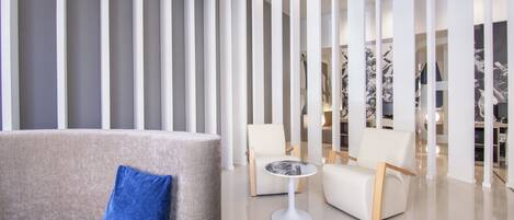 Un interior moderno con un sofá, dos sillas, una mesita y un separador decorativo.