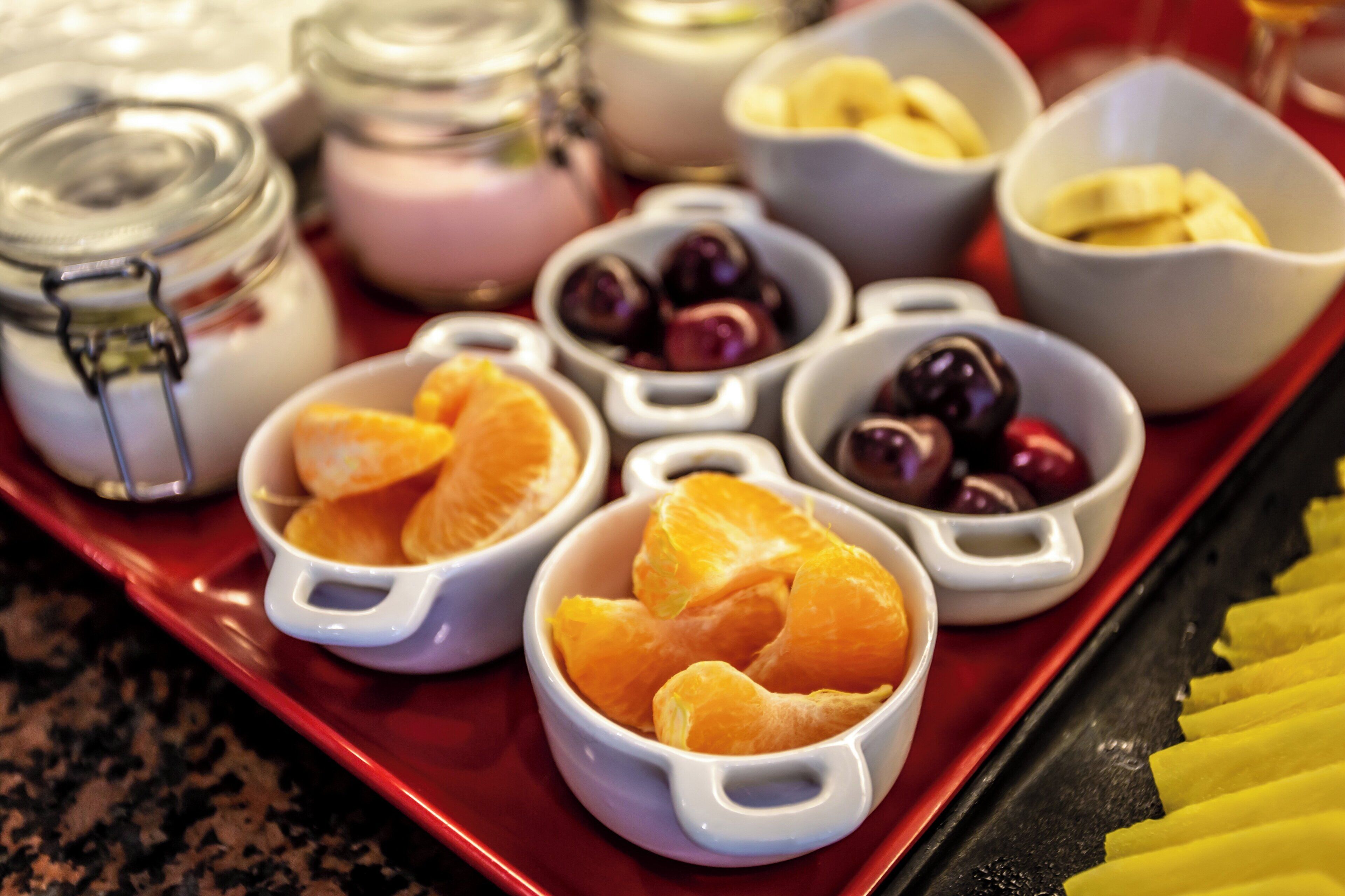 A tray with various food items including oranges, cherries, and bananas.