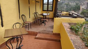 A terrace with yellow walls, tiled flooring, and outdoor seating.