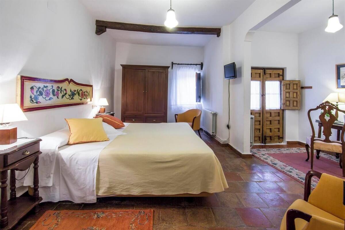 A bedroom with a bed, bedside table, lamp, and a wooden wardrobe.