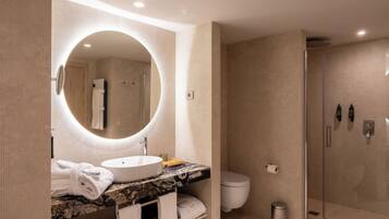 A modern bathroom with a round mirror, a bathtub, a toilet, and a glass-enclosed shower.