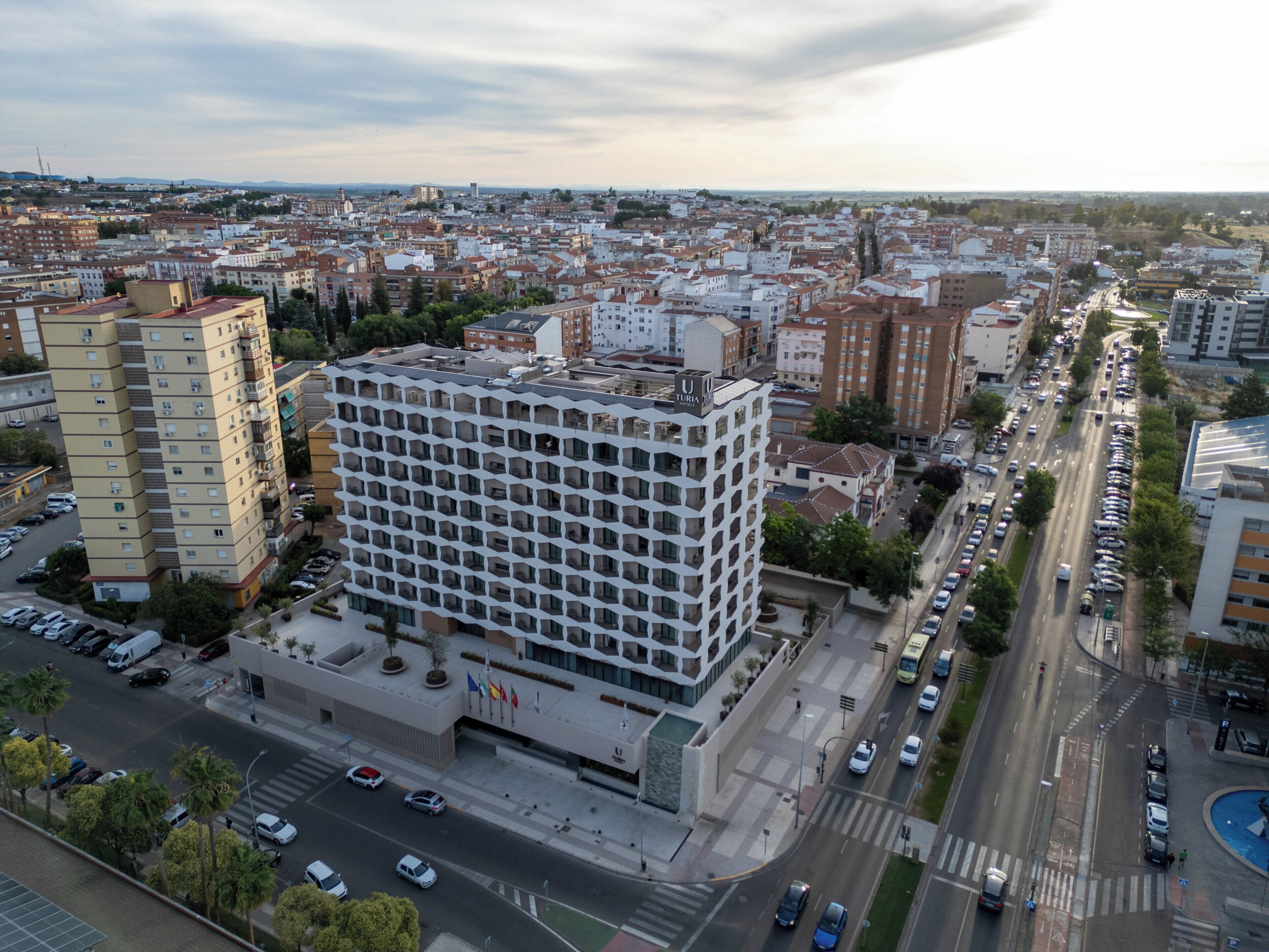 A high-rise building with a grid of windows, surrounded by a cityscape with various buildings and a busy road.