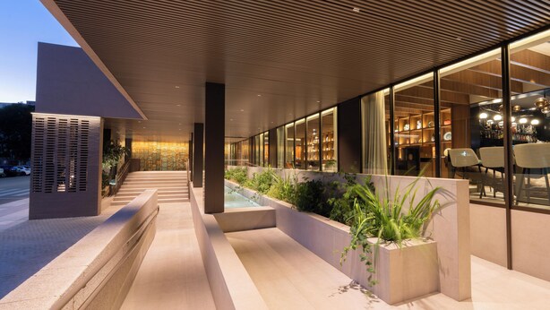 A modern building with a sloped roof, a water feature, and a seating area with tables and chairs. - Hotel Turia Badajoz (Badajoz)