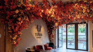 A hotel lobby with a large floral installation, a reception desk, and seating area. - Hotel Turia Badajoz (Badajoz)
