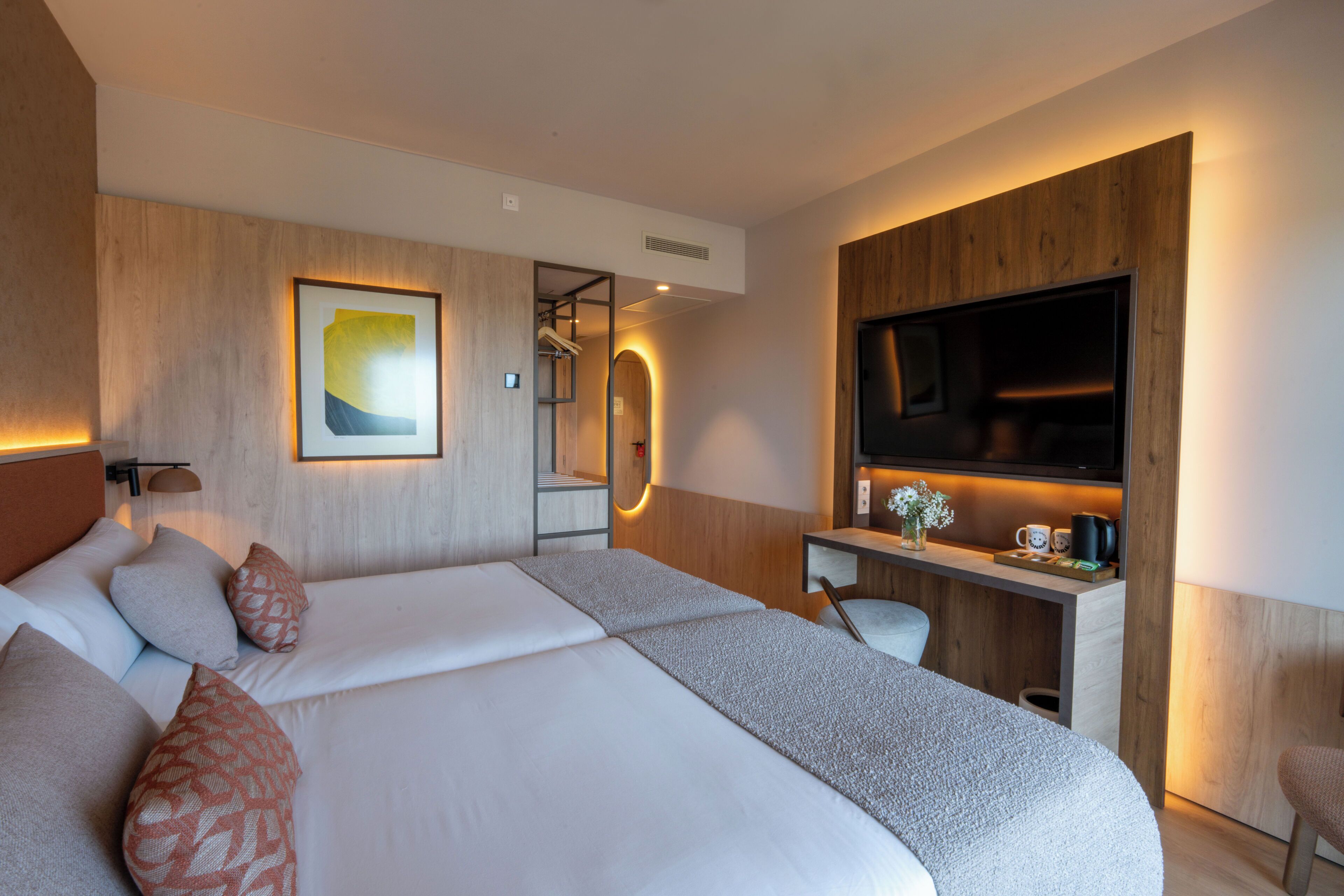 Una habitación de hotel moderna con una cama grande, un escritorio, un televisor y un espejo.