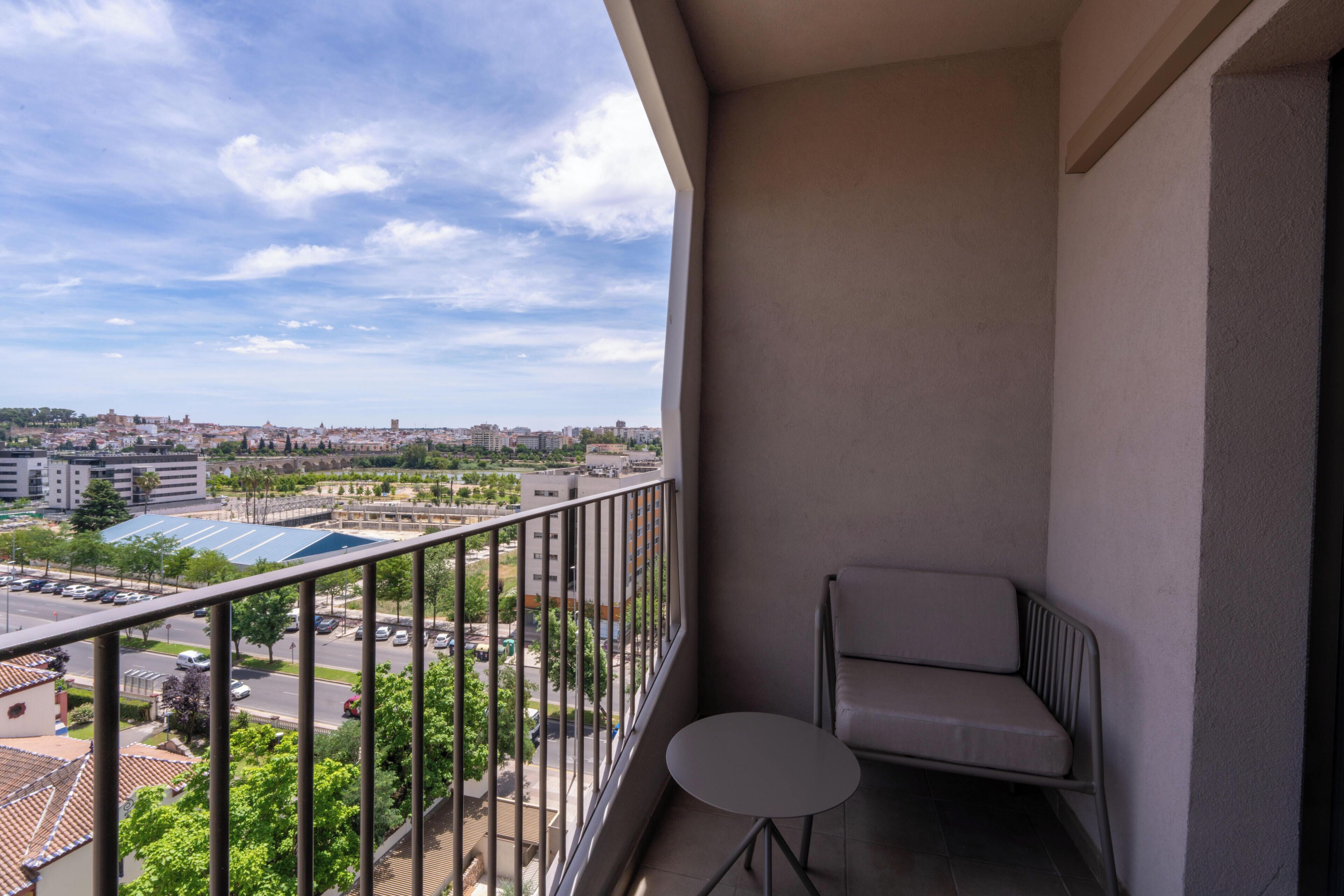 Un balcon donnant sur le paysage urbain, une petite table et une chaise.