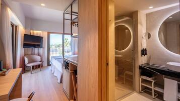 A modern hotel room with a balcony, a shower with a glass door, a flat-screen TV, and a wooden floor.