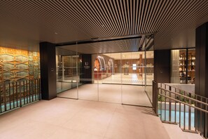 A modern hotel lobby with a glass partition, a staircase, and a patterned wall. - Hotel Turia Badajoz (Badajoz)