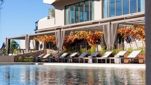 A modern hotel with a pool, sun loungers, and a covered area with autumn foliage. - Hotel Turia Badajoz (Badajoz)