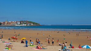 Ein überfüllter Strand mit badenden und sonnenbächelnden Menschen.