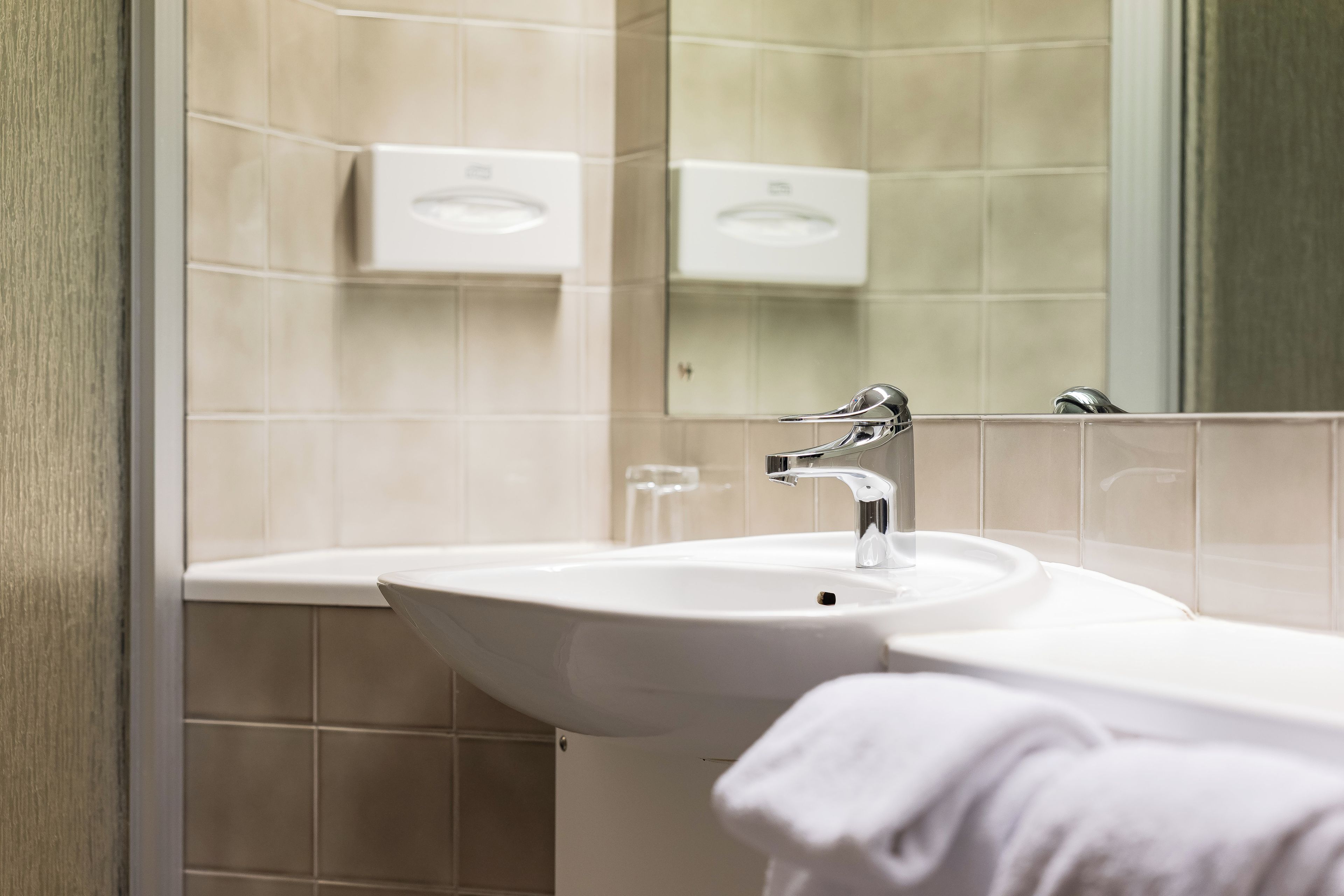 Un bany amb un lavabo, mirall i barra de tovalloles.