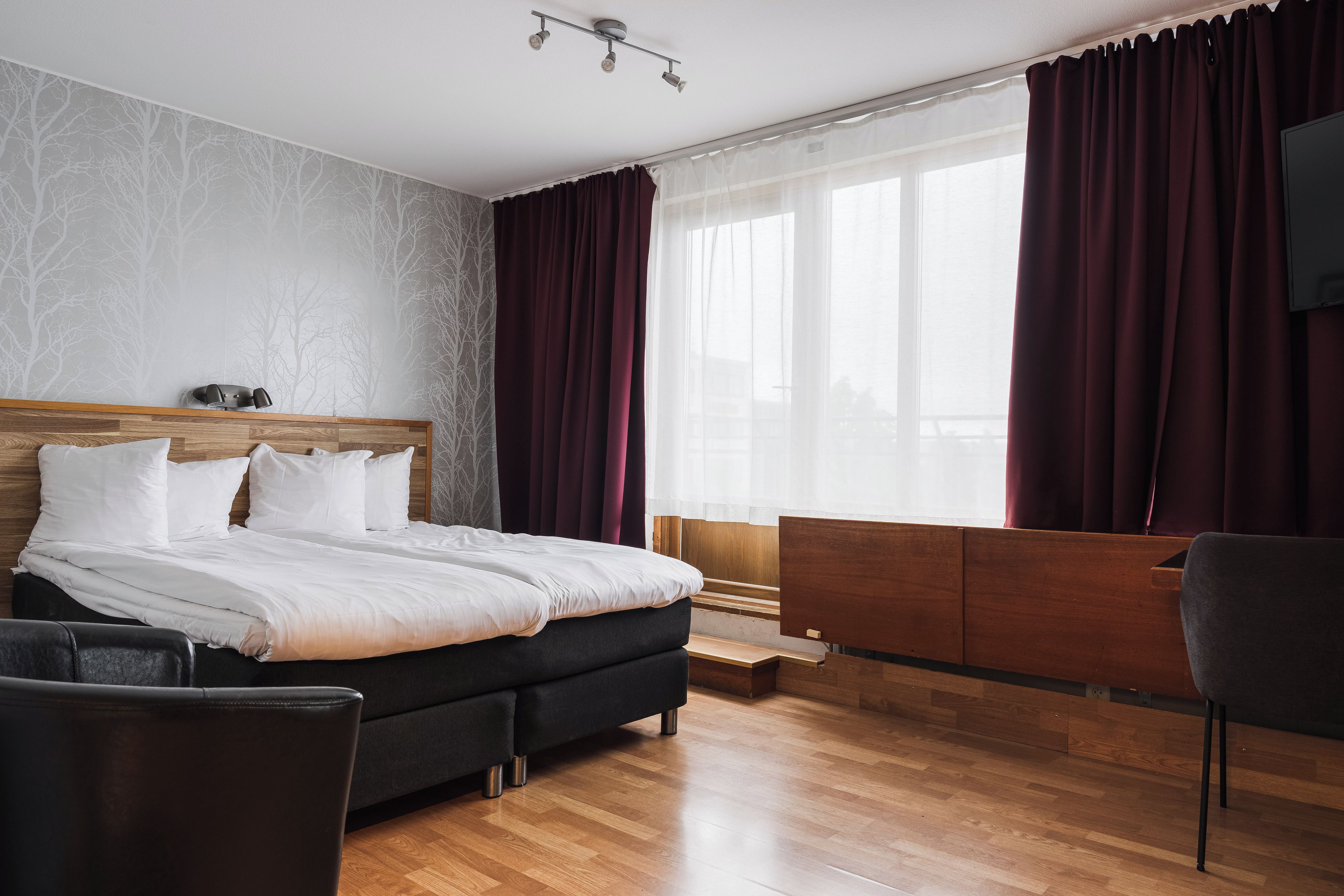 Een moderne hotelkamer met een houten bed, een bureau en een stoel.