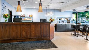 A modern reception area with a wooden counter, a clock, and a chandelier. - Best Western Malmia Hotel (Skelleftea)