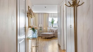 A hallway with a glass table, a lamp, a vase of flowers, and a coat rack. - Best Western Malmia Hotel (Skelleftea)