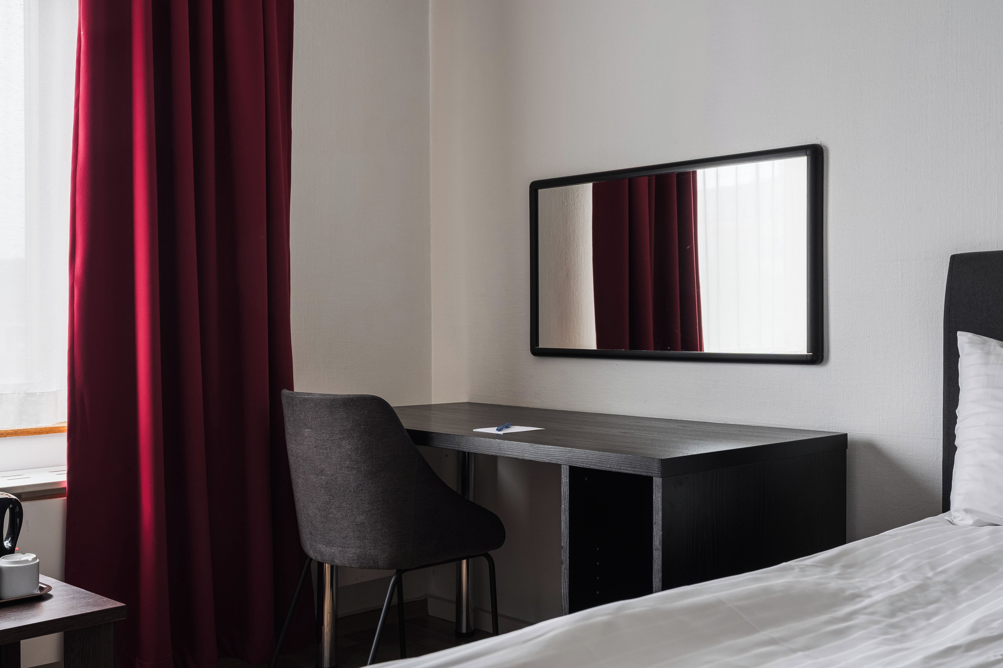 A hotel room with a desk, chair, and a bed.