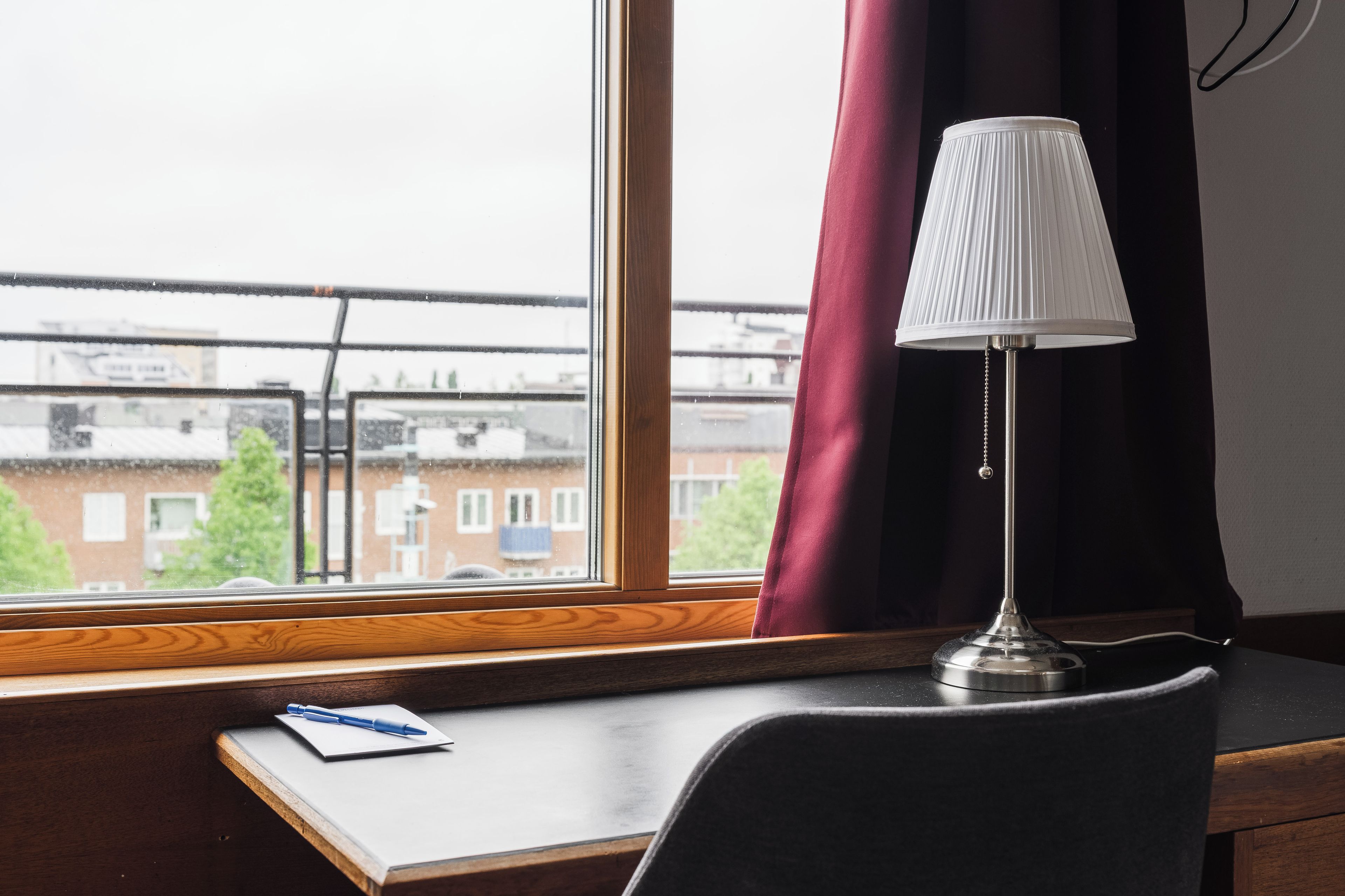 A desk with a lamp, a notebook, and a pen.