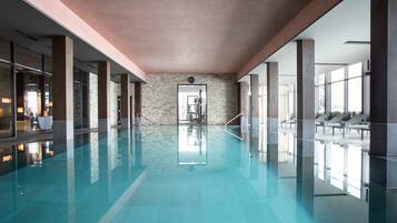 Una piscina techada, sillones reclinables de piscina