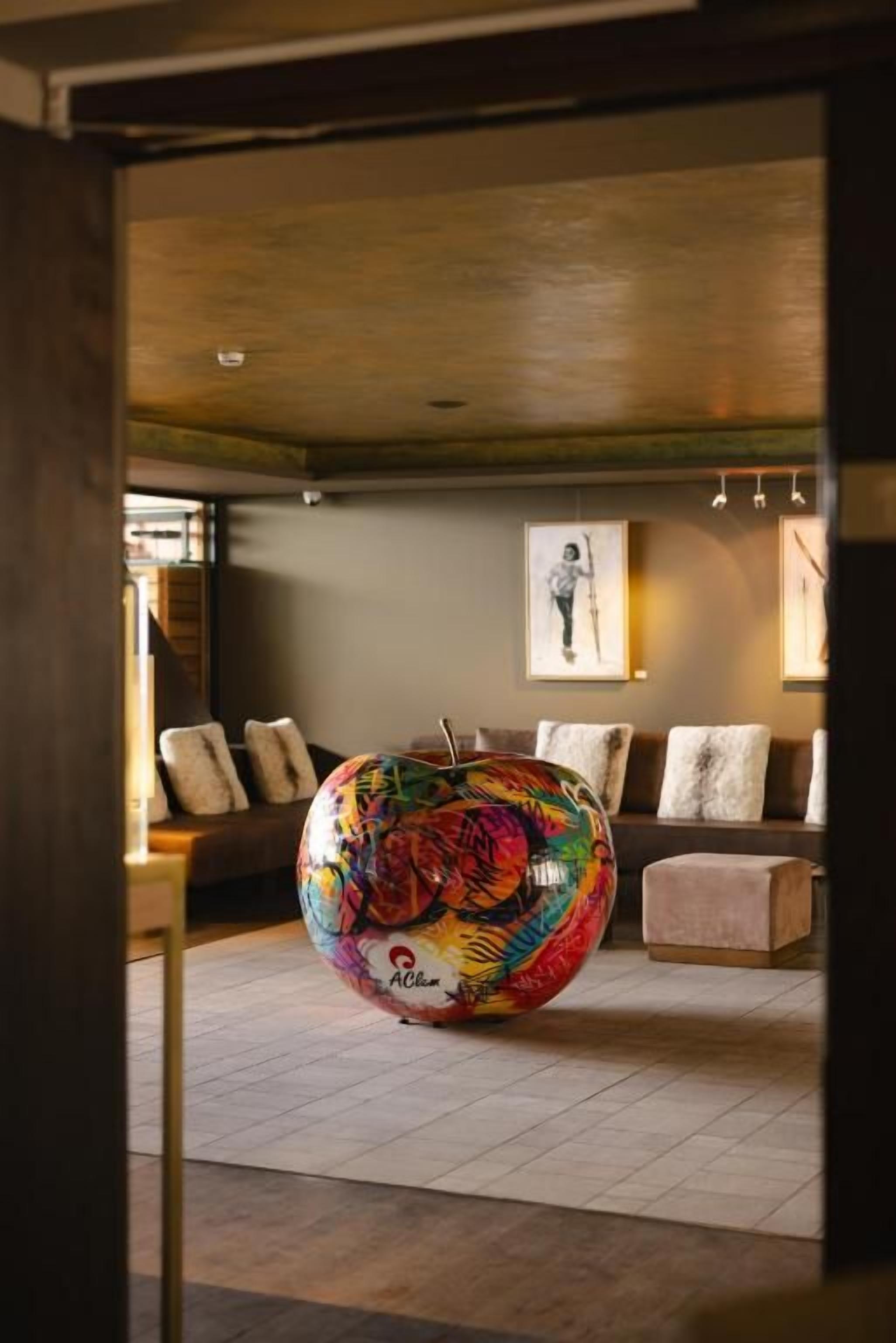 A room with a large, colorful spherical object on the floor, a sofa with cushions, and a painting on the wall.