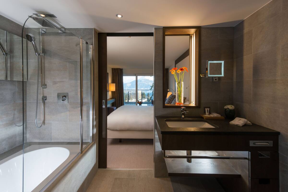 Un baño moderno con ducha de vidrio, un espejo grande y un mueble lavabo doble.